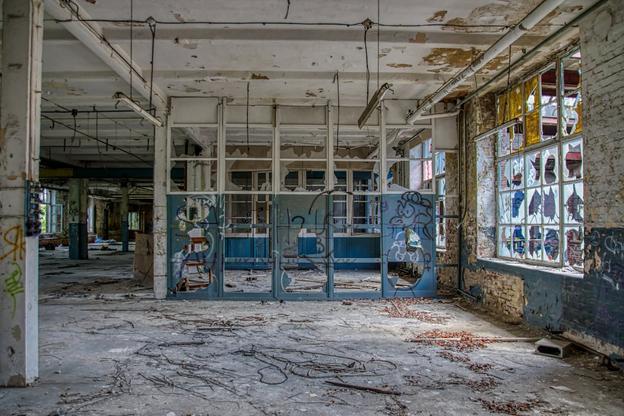 Interior of a forsaken industrial space in Leipzig adorned with graffiti and broken windows.